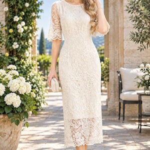 Puede incluir: Un vestido midi de color crema con un intrincado encaje floral, cuello redondo y mangas hasta el codo con bordes festoneados. El dobladillo está rematado con un borde de encaje transparente y el vestido se combina con tacones beige.