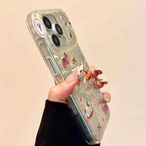 Puede incluir: Funda transparente para tel&eacute;fono con dise&ntilde;os coloridos y caprichosos. La funda presenta varias formas y patrones, incluyendo un instrumento musical y un dise&ntilde;o de punto de cruz. Una pegatina blanca con una "Y" negra es visible.