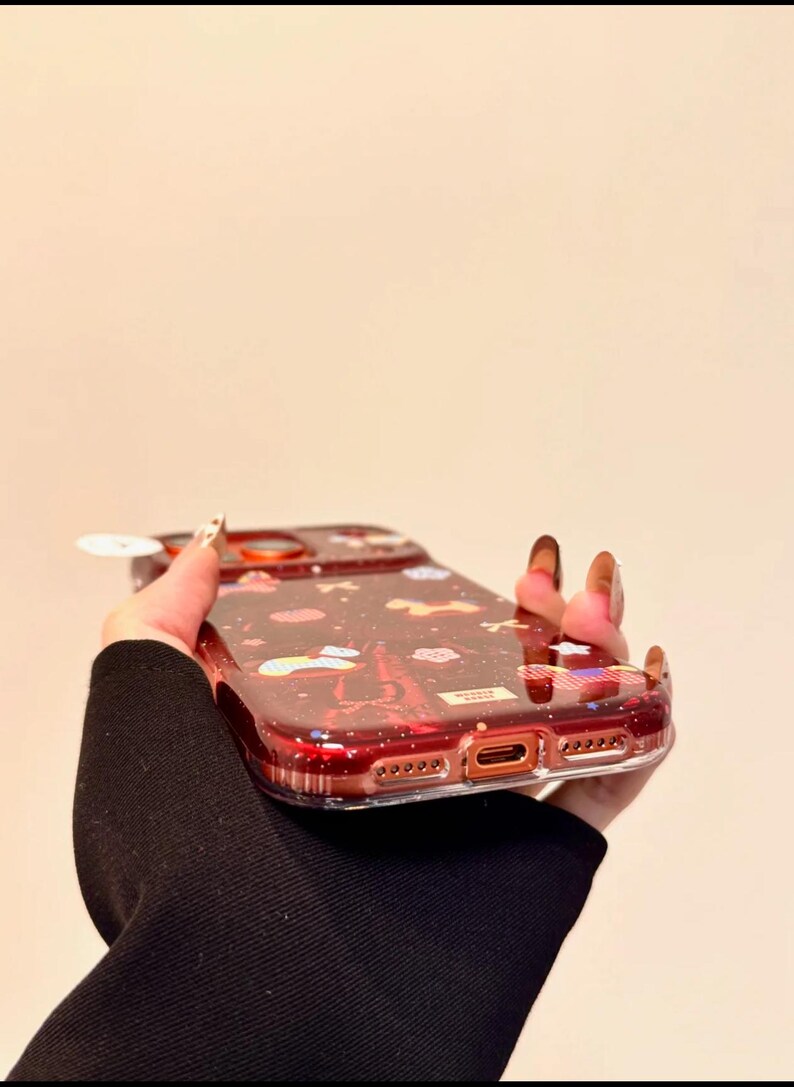Puede incluir: Una funda de tel&eacute;fono roja transparente con un dise&ntilde;o brillante que presenta nubes, estrellas y la Torre Eiffel. La funda tiene un parachoques protector y recortes para las funciones del tel&eacute;fono.