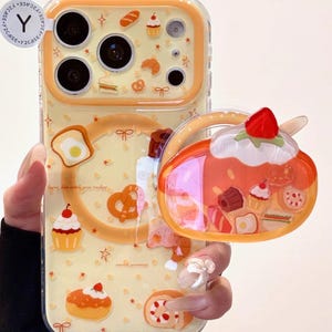 May include: A clear phone case with a yellow background and a pattern of baked goods, including croissants, cupcakes, and pretzels. A 3D dessert-shaped charm is attached. The case has the text "loving fun with your today" and "sweet yummy".