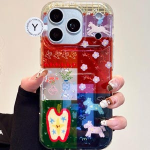 May include: Clear phone case with a vibrant design. The case has a red, white, blue, and green colour scheme with illustrations of horses, flowers, and an apple. The case has a clear border and a Y2CASE logo.