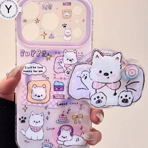 Könnte beinhalten: Transparente Handyhülle mit lila Rand und Welpen-Design. Die Hülle zeigt verschiedene Welpen-Illustrationen, den Text "Puppy", "I will be Love Happy for you" und andere Grafiken. Ein welpenförmiger Anhänger ist befestigt.