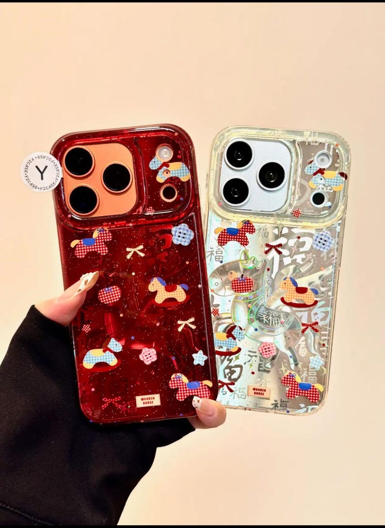 Puede incluir: Dos fundas de tel&eacute;fono con dise&ntilde;os decorativos. Una es de color rojo intenso con acabado brillante, con motivos de caballitos de juguete y lazos. La otra es transparente con dise&ntilde;os similares. Ambas fundas tienen un recorte para cuatro lentes.