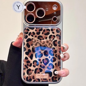 May include: A silver phone case with a leopard print design and a bow detail. The case has a clear section with a bow-shaped accent and the text "Bow leopard print". The top section has a reflective surface.