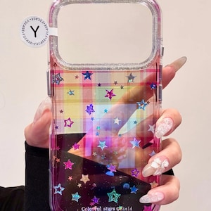 Peut inclure: Coque de téléphone transparente avec un motif d'étoiles colorées. Le boîtier a un bord transparent et un motif à carreaux avec des étoiles de différentes couleurs. Le texte "Colorful stars shield" est en bas.