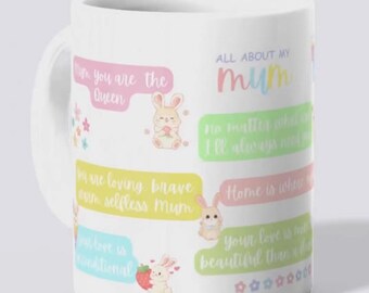 May include: A white ceramic mug featuring pastel-colored text and illustrations of small rabbits. The text includes phrases like All About My Mum, You are the Queen, and Home is where you are, accompanied by small star and flower graphics in soft hues.