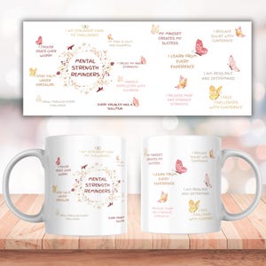 May include: White ceramic coffee mug with the text "Mental Strength Reminders" and inspirational phrases. The design includes butterflies and floral elements in shades of pink and gold. The mug is on a wooden surface.
