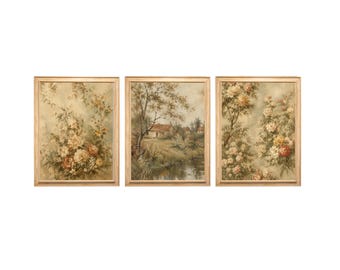 May include: A set of three framed wall art prints. The left and right prints feature detailed floral arrangements with cream, pink, and yellow blossoms. The center print depicts a landscape scene with a small house, trees, and a stream.