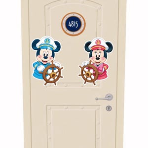 Op de afbeelding: Een beige deur met een patrijspoort-achtig bord met de tekst "4815". Twee stripfiguren, een man en een vrouw, worden afgebeeld als zeelieden die scheepsstuurwielen vasthouden. De mannelijke figuur draagt een blauw uniform, de vrouwelijke een roze uniform.