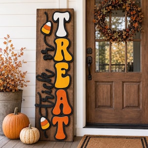 May include: A tall rectangular wooden sign with a dark brown finish featuring the vertical text "TREAT" in large, layered, colorful letters and the cursive script "trick or" in black, accented with two candy corn icons at the top and bottom.