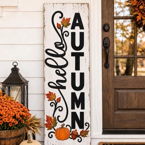 Könnte beinhalten: Ein hohes, rechteckiges Holzschild mit weißer, abgenutzter Oberfläche und dem schwarzen Schriftzug "hello AUTUMN" in einer Mischung aus Schreib- und Blockschrift. Das Design zeigt bunte Herbstblätter, einen Kürbis und eine Eichel.