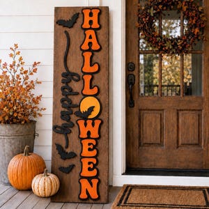 May include: A tall rectangular wooden porch sign with a dark brown finish. The sign features the vertical text HALLOWEEN in orange letters with black outlines and the word happy in black script. Three black bat silhouettes are attached.