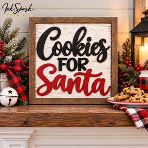 May include: A square wooden sign with a white distressed background and a dark brown frame. The sign features the black text "Cookies" and "FOR" with the red text "Santa" in a script font. The text is raised from the surface.