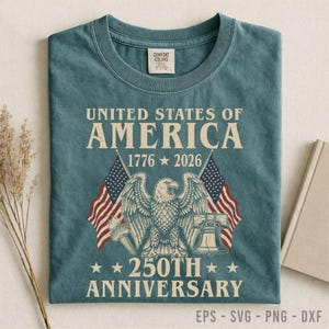 Puede incluir: Una camiseta Comfort Colors de color verde azulado con el texto "United States of America 1776-2026 250th Anniversary." El diseño incluye un águila, banderas americanas, una antorcha y una campana. La parte inferior de la camiseta tiene el texto "EPS - SVG - PNG - DXF."