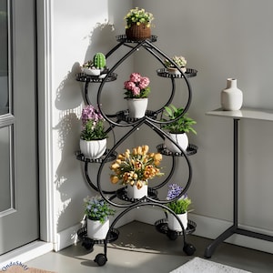 Może przedstawiać: Czarny, metalowy stojak na rośliny o kształcie serca, mieszczący różne rośliny doniczkowe. Stojak ma wiele poziomów i małe kółka ułatwiające przemieszczanie. Rośliny obejmują kaktusy, rośliny kwitnące i zieleń.