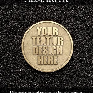 May include: A circular gold-toned metal coin with a textured edge, featuring the embossed text 'YOUR TEXT OR DESIGN HERE'. Above the coin, the text 'Atelier ALMARITA' appears, and below it, the French phrase 'Des gravures qui traversent les générations et célèbrent l'essentiel.'