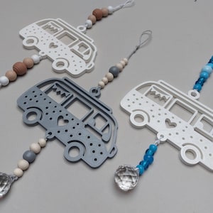 Könnte beinhalten: Drei Wohnmobil-Ornamente mit ausgestanzten Herz- und Punktmustern. Jedes Ornament hängt an einer Schnur, die mit verschiedenen Perlen, darunter Holz- und Kunststoffkugeln, sowie einem klaren, facettierten Kristallprisma verziert ist.