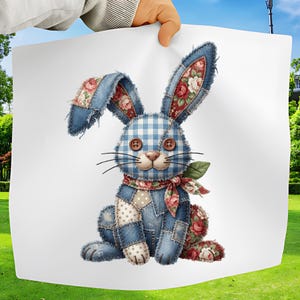 Op de afbeelding: Een grillige patchwork konijn illustratie. Het konijn heeft denim blauwe stof met bloemen- en ruitaccenten. Het heeft knoopogen, een roze neus en een bloemen sjaal. Het konijn zit op een witte achtergrond.