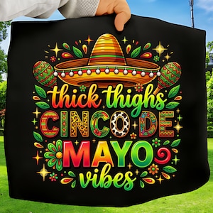 Peut inclure: Textile noir avec un motif coloré du Cinco de Mayo. Le motif comprend un sombrero, des maracas et le texte "thick thighs CINCO DE MAYO vibes" aux couleurs vives. Des étoiles et des éléments floraux ornent le texte.