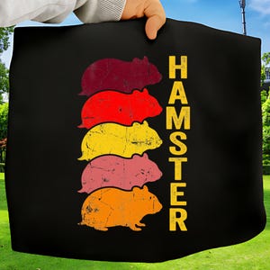 May include: Black fabric with a retro design featuring stacked hamsters in burgundy, red, yellow, pink, and orange. The word "HAMSTER" is printed vertically in yellow. The design has a distressed, vintage look.