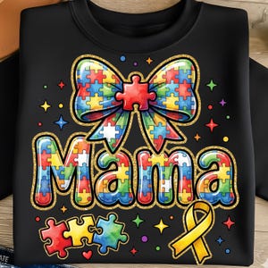 Puede incluir: Sudadera negra con un lazo colorido de piezas de rompecabezas y la palabra "Mama" en letras de piezas de rompecabezas. El diseño incluye una cinta amarilla y estrellas dispersas. El diseño está delineado con purpurina dorada.