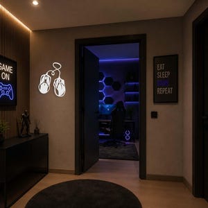 May include: A modern gaming room with neon signs. A black framed sign says "GAME ON" with a blue controller graphic. Another sign says "EAT SLEEP GAME REPEAT". White neon mouse and a black console table.