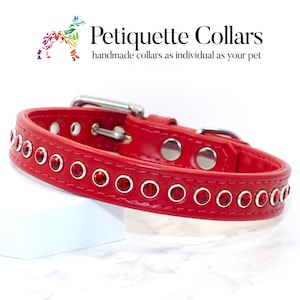 May include: Red leather dog collar with silver buckle and red crystal accents. "Petiquette Collars" is written in the top left corner of the image. "handmade collars as individual as your pet" is written below the company name.