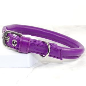 Puede incluir: Un collar morado para perros con un dise&ntilde;o redondeado. Cuenta con una hebilla de metal plateado y una anilla en D para sujetar la correa. El collar est&aacute; hecho de un material liso y de color s&oacute;lido.