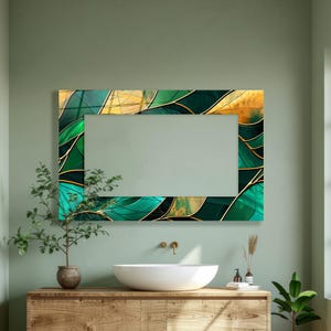 May include: A rectangular mirror with a decorative frame. The frame features a stained glass design with shades of green, gold, and black. The mirror is mounted above a wooden vanity with a white sink and a small plant.