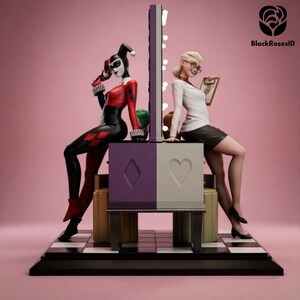 Può includere: Una statuetta da collezione a doppia faccia che raffigura un personaggio in costume da giullare rosso e nero su un lato e un personaggio con camicetta bianca e gonna scura sull'altro. Sono seduti schiena contro schiena su una base viola e bianca.
