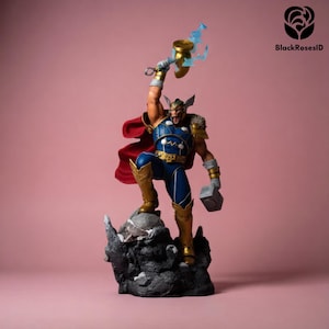 Op de afbeelding: Een gedetailleerd beeldje van Thor, de Marvel Comics-superheld, staand op een rotsachtige basis. Hij draagt een blauw en goud kostuum met een rode cape en houdt zijn hamer, Mjolnir, omhoog, met blauwe bliksemeffecten. Het beeldje staat tegen een roze achtergrond.