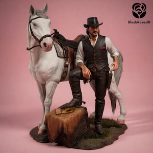 May include: A detailed figurine of a cowboy in a black hat and vest, leaning on a white horse. The cowboy is wearing a white shirt, dark pants, and boots. A saddle is on the horse. The figurine is on a base with a small wooden box and gold bars.