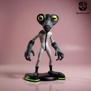 May include: A figurine of a gray alien character with large yellow eyes, wearing a white jumpsuit with a black stripe. The figure stands on a black base with green accents. The background is a solid pink color.