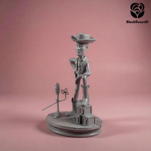 K&ouml;nnte beinhalten: Graue Figur eines Cowboy-Charakters, der einen Hut und Stiefel tr&auml;gt und auf einer Basis mit Spielzeugbl&ouml;cken steht. Ein Mikrofon und eine Blume befinden sich ebenfalls auf der Basis. Der Hintergrund ist einfarbig rosa.
