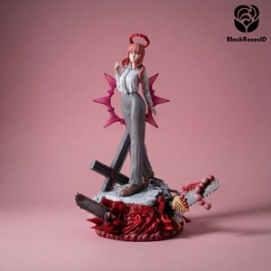 May include: A Makima anime character figurine featuring a woman with pink hair, a white button-down shirt, and gray trousers. The figure stands on a base with a red, spiky halo, a dark cross, a chainsaw blade, and a yellow chainsaw-headed creature.
