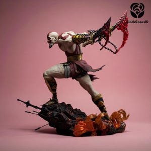 Puede incluir: Figura detallada de un personaje musculoso en una pose dinámica, sosteniendo un arma encadenada con una hoja roja. La figura está sobre una base rocosa con llamas y lleva una armadura roja y dorada. El fondo es rosa liso.