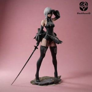 May include: A collectible figurine of a character with short white hair, wearing a black outfit with lace details, a blindfold, and long black stockings. The figure holds a long, thin silver sword in one hand and stands on a textured base.