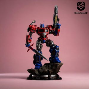 Puede incluir: Figura de acción detallada de Optimus Prime, el líder de los Autobots, en una pose dinámica. La figura es predominantemente roja, azul y plateada, sosteniendo un bláster y una espada. La figura está sobre una base rocosa sobre fondo rosa.