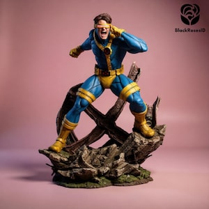 May include: A Cyclops action figure in a dynamic pose, clad in a blue and yellow costume. The figure stands on a rocky base with a wooden structure, set against a pink backdrop. The figure has a red visor and is yelling.