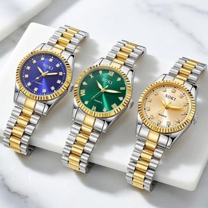 May include: Three SOKI quartz watches with gold and silver bands. The watches have different colored faces: blue, green, and gold. Each watch has a gold bezel and a silver and gold link band. The watch faces have the word "SOKI" printed on them.