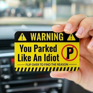 May include: A yellow and black warning card with the text "WARNING You Parked Like An Idiot" and a no parking symbol. The card also includes the text "FLIP OVER TO FIND THE REASON".