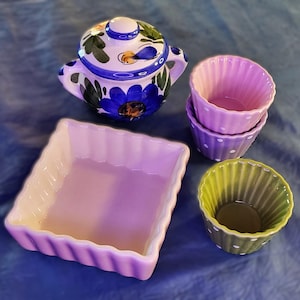 Peut inclure: Ensemble de céramiques de cuisine comprenant un sucrier à couvercle orné de motifs floraux bleus et verts, un plat à four carré et trois petits ramequins colorés. Les ramequins sont roses et verts avec des pois blancs.