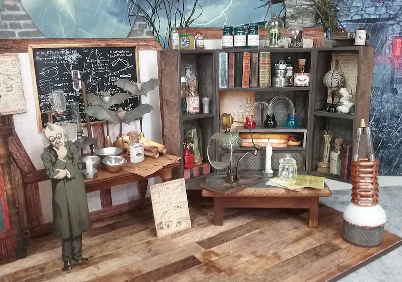May include: A miniature dollhouse room with a scientist's laboratory theme. The room features a wooden table with a chalkboard, a shelf with various glass bottles and jars, and a small table with a magnifying glass and a candle. There is a small figure of a scientist standing in the room.