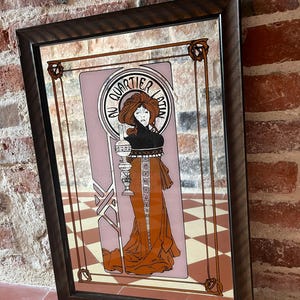 Peut inclure: Un miroir mural rectangulaire avec un cadre brun foncé présentant une illustration imprimée d'une personne aux cheveux roux tenant une lampe. Le motif inclut un fond violet clair, des accents bruns et le texte "AU QUARTIER LATIN" dans un cadre circulaire.