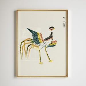 Puede incluir: Una impresión enmarcada de un pájaro estilizado de estilo japonés. El pájaro presenta una larga cola y está representado en tonos de azul, amarillo, rojo y negro. La impresión está en un marco dorado e incluye texto japonés en el lado derecho.