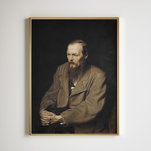 May include: A framed portrait of a man with a long, reddish-brown beard and a serious expression. He wears a light brown coat and has his hands clasped. The background is a dark, solid color, and the frame is gold.