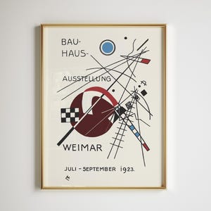May include: Framed Bauhaus exhibition poster in a gold frame. The poster displays abstract geometric shapes in red, black, blue, and white on a cream background. Text includes "BAUHAUS-AUSSTELLUNG WEIMAR" and "JULI - SEPTEMBER 1923."