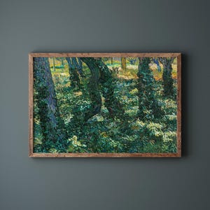 May include: A framed art print of a forest scene. The painting depicts trees with green foliage and sunlight filtering through the leaves. The artwork is in a wooden frame and hangs on a dark gray wall.