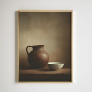 以下が含まれることがあります： 茶色の取っ手付き陶器のジャグと小さな白いボウルを描いた、額入りの静物画。このアートワークは、温かみのあるニュートラルな色使いと金色のフレームで、素朴な魅力と静けさを醸し出しています。