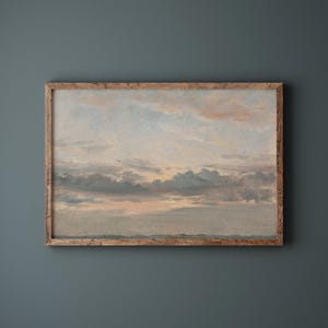 May include: A framed landscape painting depicts a serene sky with soft clouds in shades of gray, pink, and blue. The artwork is encased in a rustic, light brown wooden frame, creating a vintage aesthetic. The painting evokes a sense of tranquility.